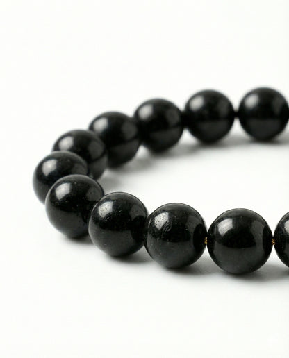 Natural Black Obsidian beaded bracelet featuring shiny 8mm black stones on white background.