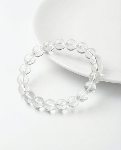 Natural Clear Quartz beaded bracelet with transparent round gemstones on black background.