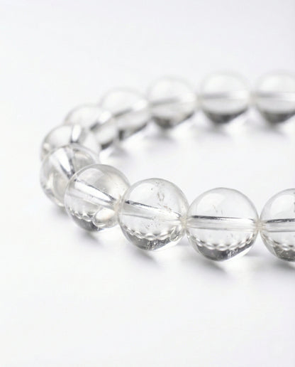 Natural Clear Quartz beaded bracelet with transparent round gemstones on black background.