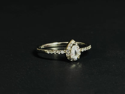Teardrop White Topaz ring with halo setting and pave silver band on black background.